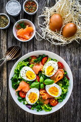 Salmon salad - smoked salmon hard boiled eggs and green vegetables on wooden table
