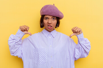 Young mixed race woman wearing a beret isolated on yellow background showing thumb down and...
