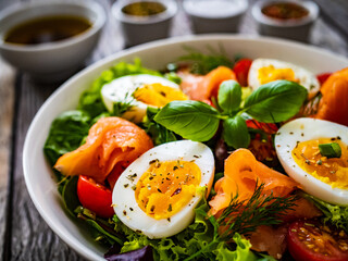 Salmon salad - smoked salmon hard boiled eggs and green vegetables on wooden table
