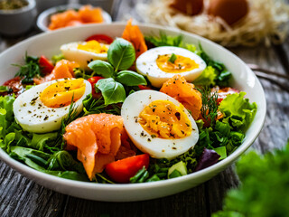Salmon salad - smoked salmon hard boiled eggs and green vegetables on wooden table
