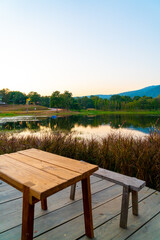 wood bench with beautiful lake at Chiang Mai with forested mountain and twilight sky