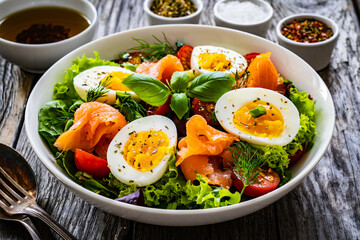 Salmon salad - smoked salmon hard boiled eggs and green vegetables on wooden table

