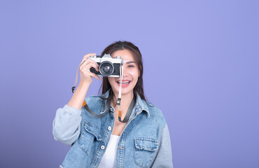 Portrait of a young smiling woman filming with retro camera isolated on the pink background