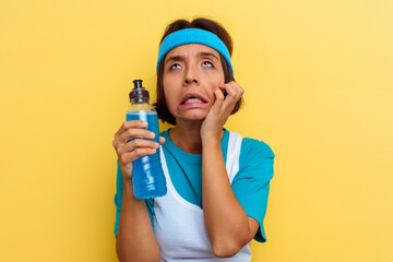 Young sport mixed race woman isolated drinking an energy drink on yellow background
