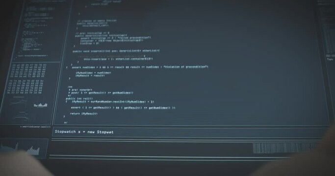 Hacker programmer types wildly on keyboard and coding program on the screen in the background.