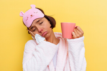 Young mixed race woman with a cold drinking a tea on yellow background