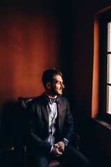 Morning of the groom. The groom is preparing to meet the bride. Waiting in the brown room. Portrait of a young businessman.