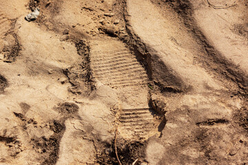 Footprint of a boot on muddy sand after low tide, waves on the surface