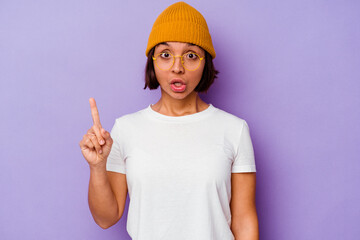 Young mixed race woman wearing a wool cap isolated on purple background having some great idea, concept of creativity.