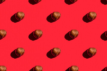 Hazelnuts background. A trendy sunlight pattern made of hazelnuts against a bright red background. Colorful pattern. Top view