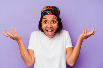 Young mixed race woman wearing a bandana isolated on purple background receiving a pleasant surprise, excited and raising hands.