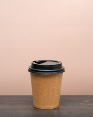 coffee to go in a disposable cup on the table and pink background. space for text