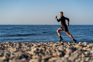 Adult man running on the stone beach