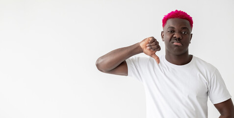 Fototapeta premium Refusing man. Dislike gesture. Bad choice. Looser blaming. Skeptic emotion. Stylish disgusted african guy with bright pink hair showing disapproval sign isolated white copy space.