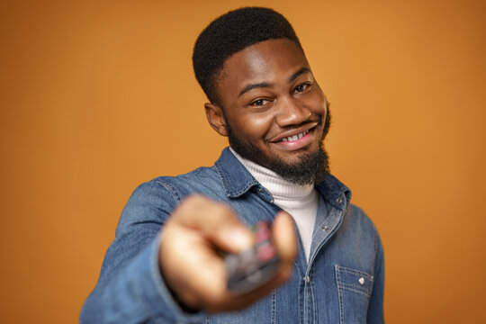 Young African Man Pushing Button On TV Remote, Close Up Portrait