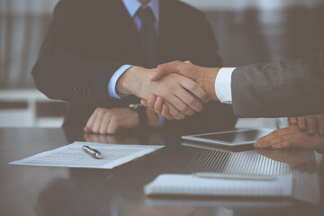 Handshake as successful negotiation ending, close-up. Unknown business people shaking hands after contract signing in modern office