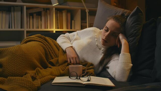 woman fell asleep why she was reading book. evening scene at home	