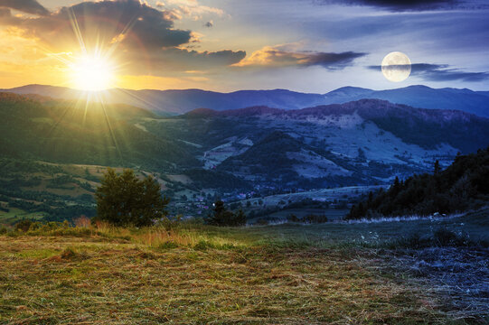 day and night time change above the mountainous rural landscape. grassy meadow on top of a hill. clouds above the ridge with sun and moon. view in to the distant valley at twilight
