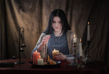 young witch conjures with burning candles on  dark background