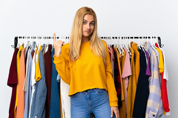 Young Uruguayan blonde woman in a clothing store pointing with the index finger a great idea