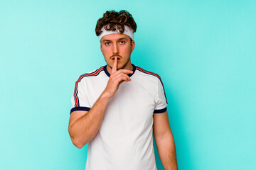 Young sport caucasian man isolated on blue background keeping a secret or asking for silence.
