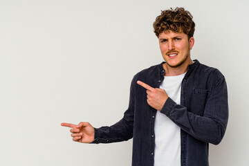 Young caucasian man isolated on white background shocked pointing with index fingers to a copy space.