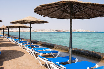 Sun loungers and thatched umbrellas along beach Blue beach chairs with Sea View