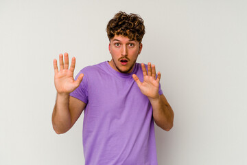 Young caucasian man isolated on white background being shocked due to an imminent danger
