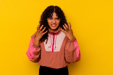 Young mixed race woman isolated on pink background upset screaming with tense hands.