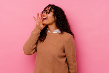 Young mixed race woman isolated on pink background shouting and holding palm near opened mouth.