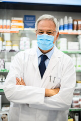 Senior pharmacist wearing a mask due to coronavirus pandemic in his store