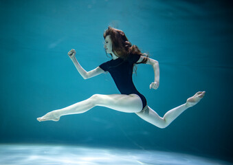  beautiful girl in a black leotard doing gymnastic exercises underwater on a blue background 