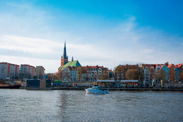 Fototapeta premium view of the old town, view of the city center, river and passing boat, wooden platform before modern city