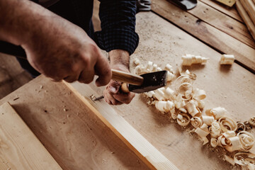 Hands of a carpenter working with chisel and hammer
