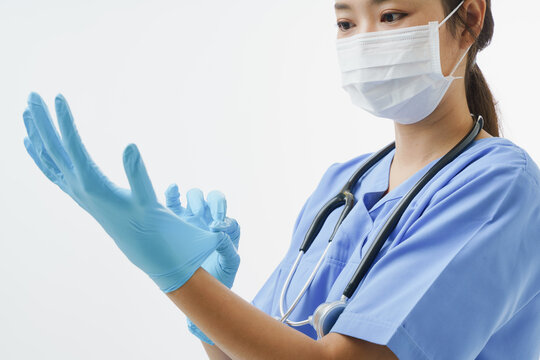 Close up assian female doctor or nurse wearing protective mask while putting  gloves on white background with copy space. Concept of Health care in hospital.