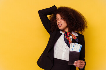 Young african american air hostess holding a plane tickets isolated on yellow background  touching...