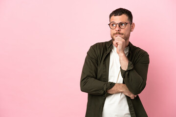 Young Brazilian man isolated on pink background having doubts and thinking