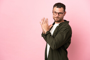 Young Brazilian man isolated on pink background scheming something