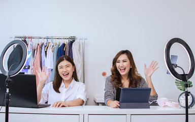Two asian beautiful female bloggers smiling with happiness and joyfulness, greeting people,...
