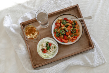 Mixed Bell-pepper Salad with Lettuce egg wrap on a brown tray in room with plants and sunshine through the window