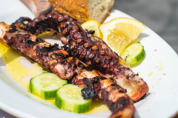 Octopus dinner on a white plate, with fork and knife showing