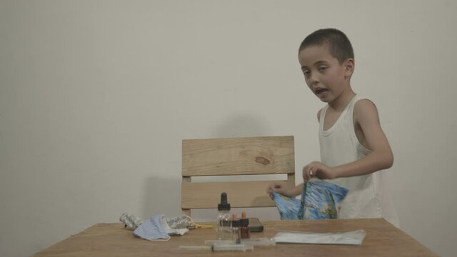 The cute boy enjoyed wearing a Hawaiian shirt over a white tank top in a white background. .Shoot in the studio with the Black Magic 6K Camera.