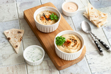  Bowl of hummus, traditional Jewish, Arabian, Middle Eastern food from chick-peas with deeps and with pita flatbread on ceramic tile background. Close up, selective focus