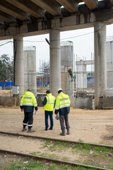 three construction foremen confer at a construction site back view