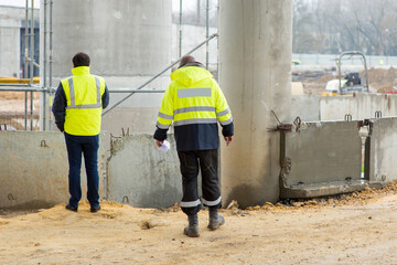 two construction managers confer at a construction site, back view