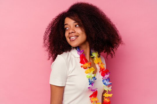 Young african american woman wearing a hawaiian stuff looks aside smiling, cheerful and pleasant.