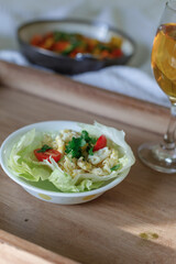 Mixed Bell-pepper Salad with Lettuce egg wrap on a brown tray in room with plants and sunshine through the window