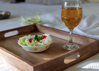 Lettuce egg wrap on a brown tray in room with a glass of drink on bed
