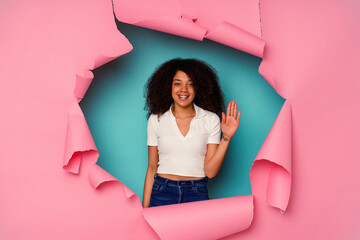 Young African American woman in torn paper isolated on blue background smiling cheerful showing number five with fingers.