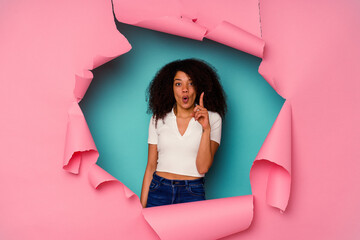 Young African American woman in torn paper isolated on blue background having some great idea, concept of creativity.